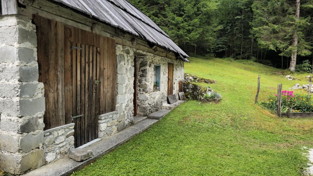 Lesena in kamnita tradicionalna hiša v Trenti, umeščena v alpsko pokrajino Triglavskega narodnega parka